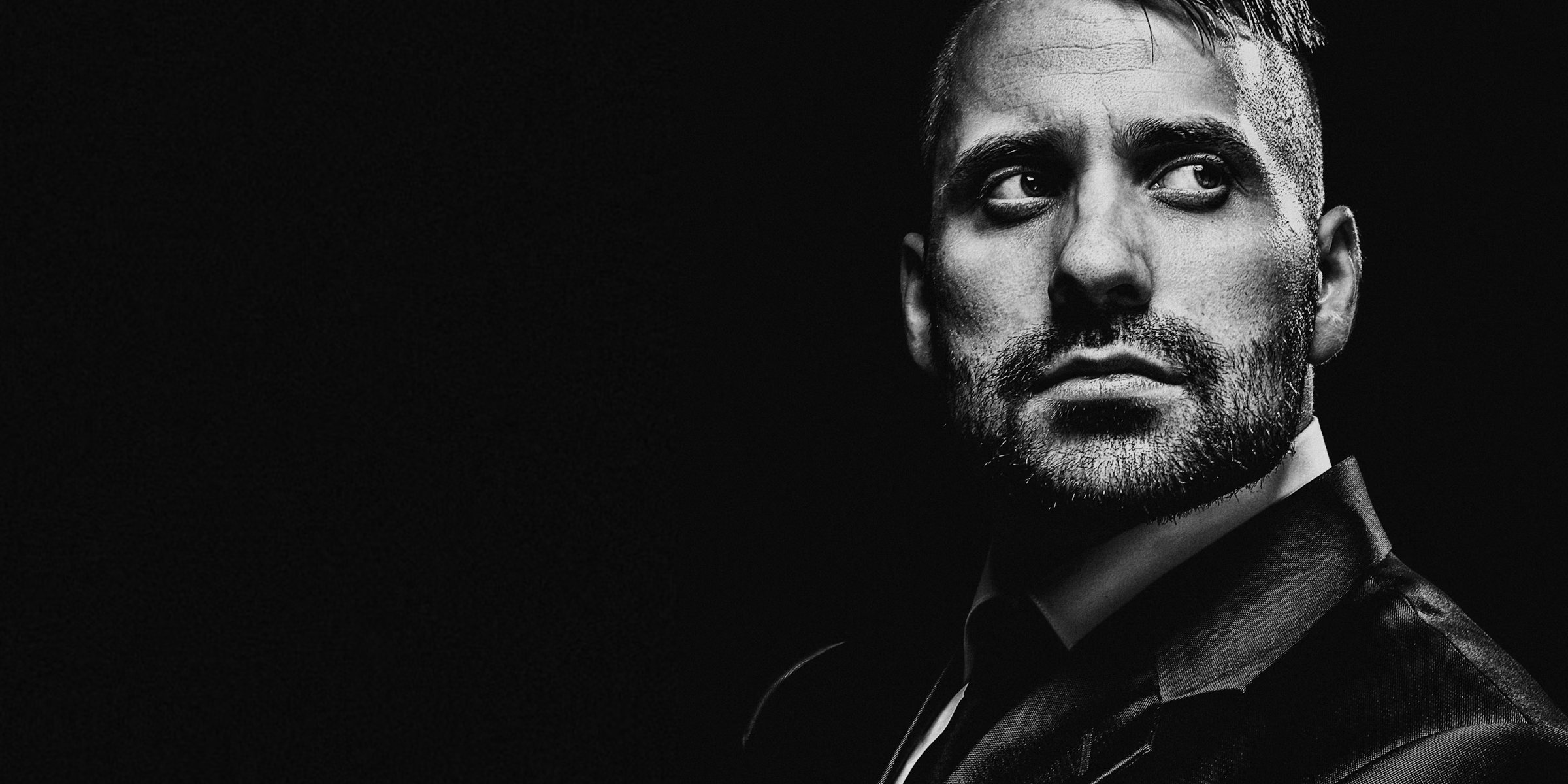 Retrato de estúdio em preto e branco, homem de terno com o olhar voltado para o lado